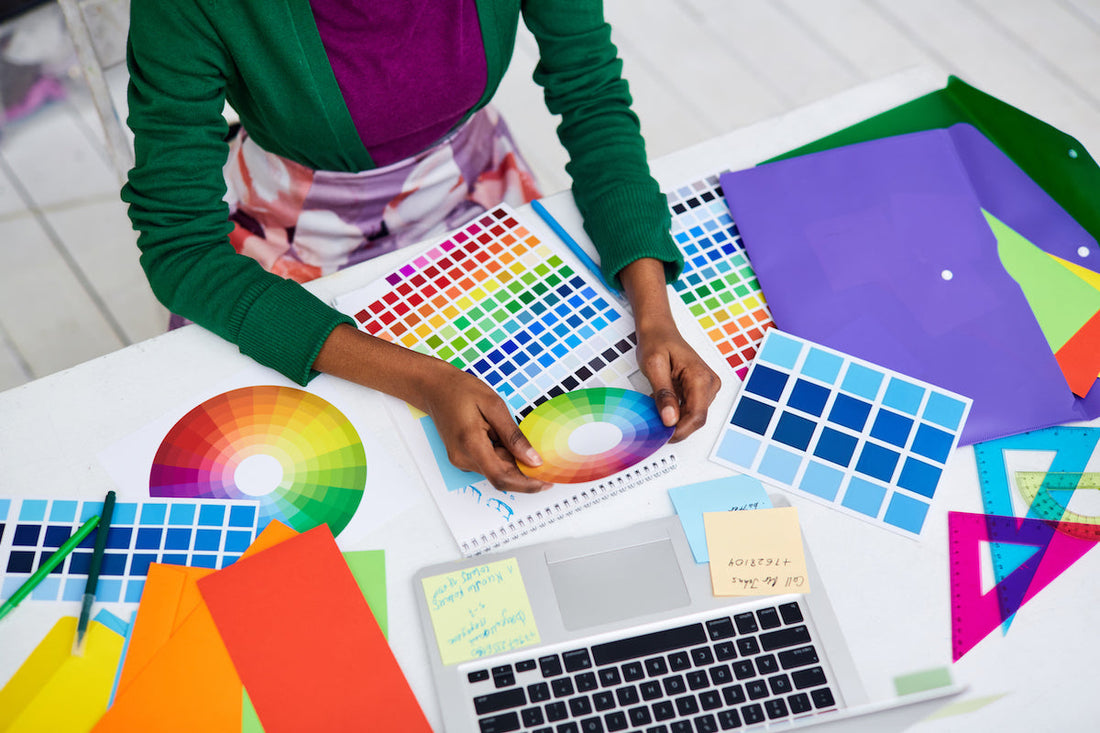Designer working with colour wheels, swatches and coloured paper on a desk