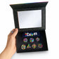 Hand holding the open Septem Aleae display box with all seven colour mixing dice inside